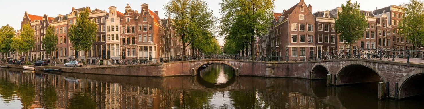 Canal d'Amsterdam bordé de maisons typiques, illustrant le modèle du coffeeshop néerlandais
