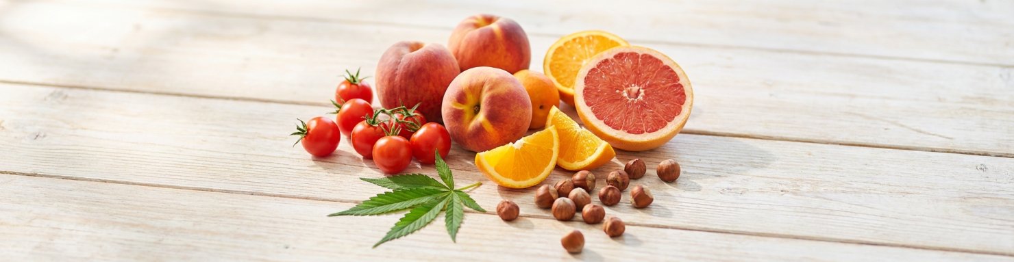 Pêche, tomate, agrumes, noisettes et feuille de cannabis illustrant le syndrome cannabis-fruits-légumes