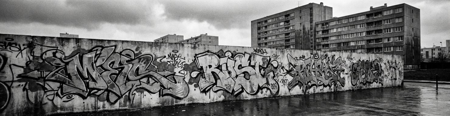 Mur de banlieue avec graffitis, ambiance argot urbain français évoquant l'origine verlan du mot teush